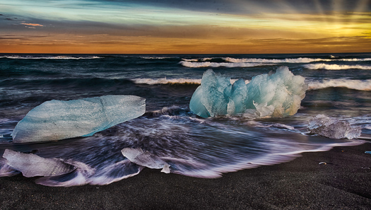 Chunks of ice on near a beach at sunset