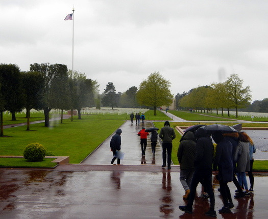 People on wide walkway through grassy area on a rainy day