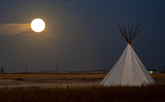 Moon over a grassland with a tepee